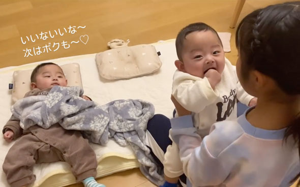 双子の赤ちゃんをあやす9歳の姉