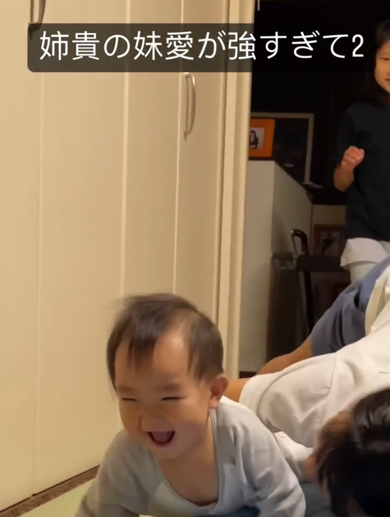姉に捕まって満面の笑顔の赤ちゃん