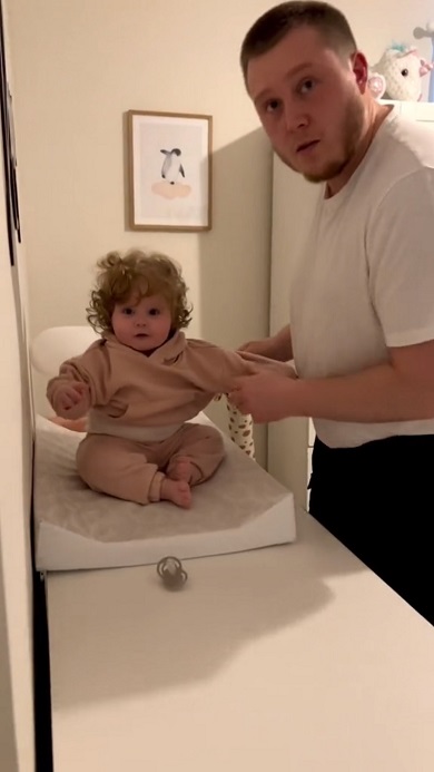 小さな娘に服を着せようと四苦八苦するパパ