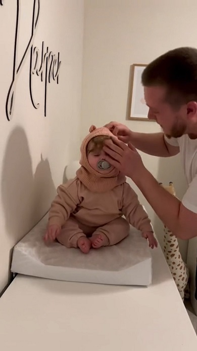 小さな娘に服を着せようと四苦八苦するパパ