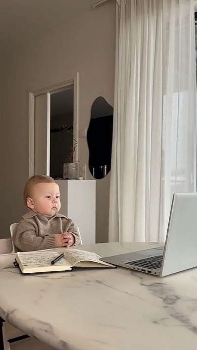 会社の重役のようにPCの画面を眺める赤ちゃん