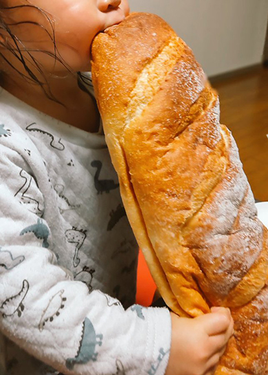 巨大なパンを丸かじりする女の子