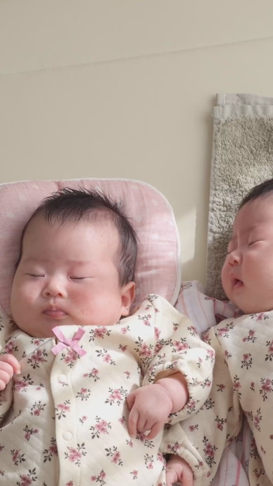 陽だまりの中で並んで寝る双子の赤ちゃん