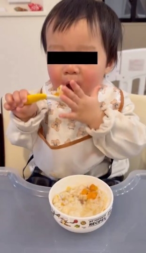 スプーンを口もとに運ぶ赤ちゃん