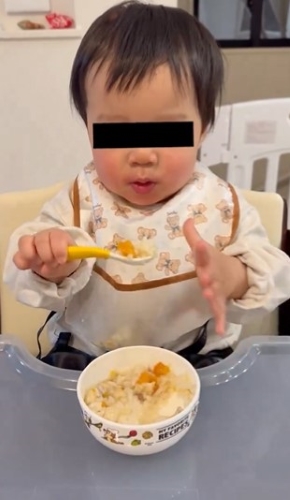 スプーンを口もとへ運ぶ赤ちゃん