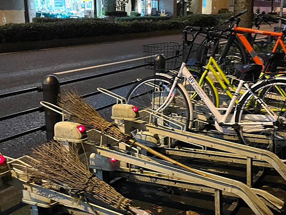 駐輪場に竹ほうきが駐めてある写真