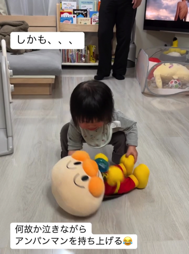 おもちゃを一生懸命持ち上げようとする赤ちゃん