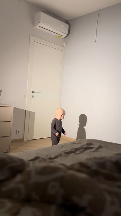 壁に映った自分の影と遊んでいる男の子