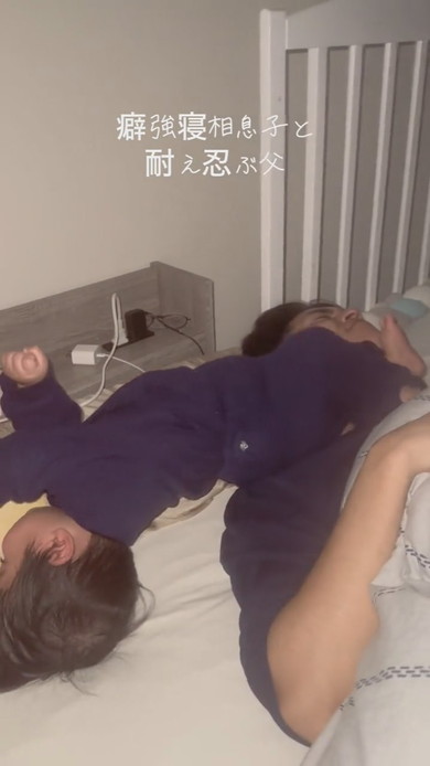 激しい寝相の息子と耐える父が並んで寝ている光景
