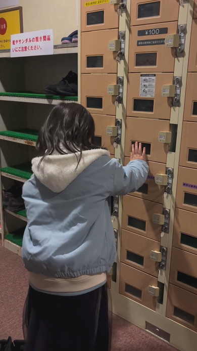 シューズロッカーの前で靴をどこに入れようか悩んでいる女の子