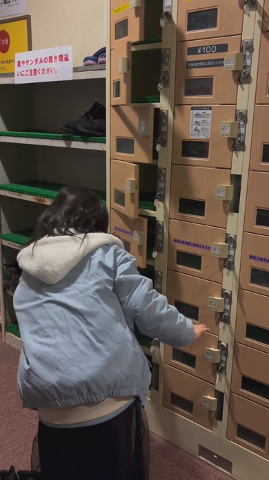 シューズロッカーの前で靴をどこに入れようか悩んでいる女の子