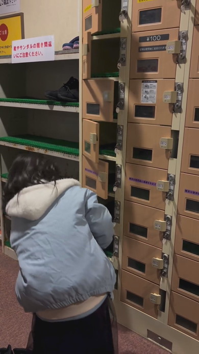 シューズロッカーの前で靴をどこに入れようか悩んでいる女の子