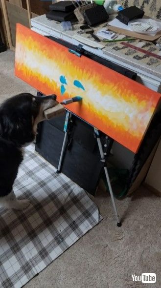 絵筆をくわえて絵を描く犬