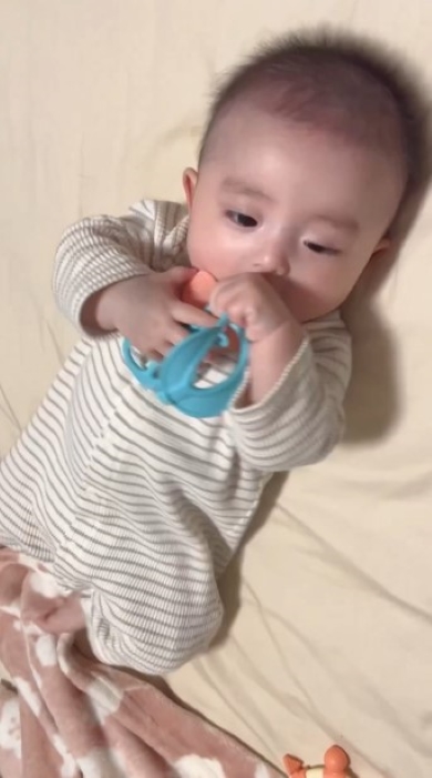 歯がためを口もとに持っていく赤ちゃん