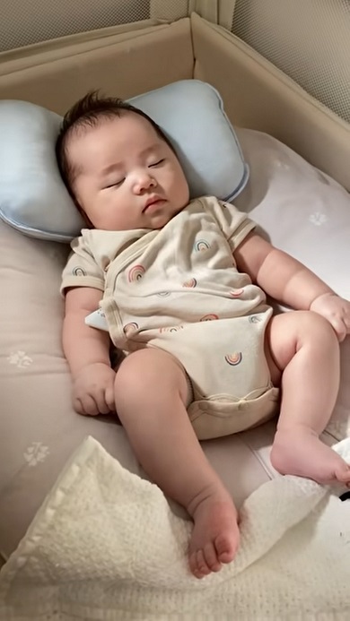 まゆ毛付近を押さえつけて赤ちゃんを寝かしつけようとする