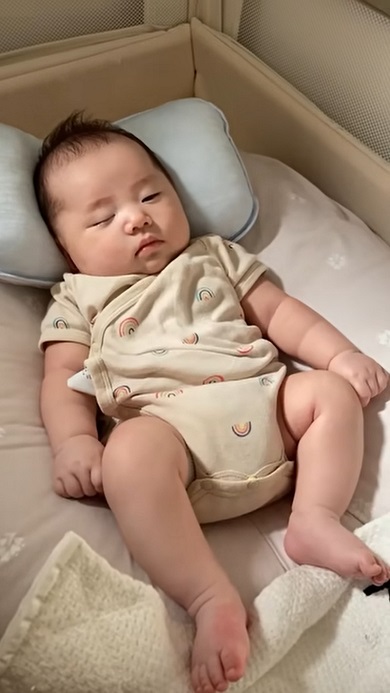 まゆ毛付近を押さえつけて赤ちゃんを寝かしつけようとする