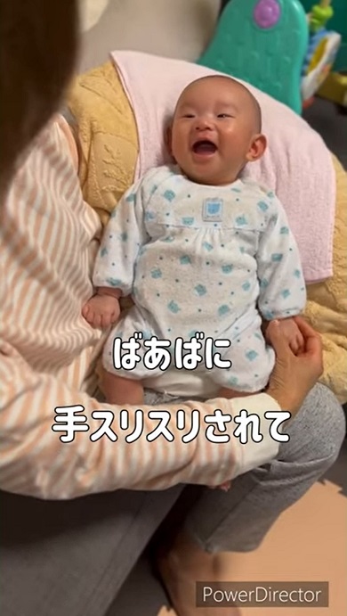おばあちゃんに手をさすってもらいうれしくなった赤ちゃん