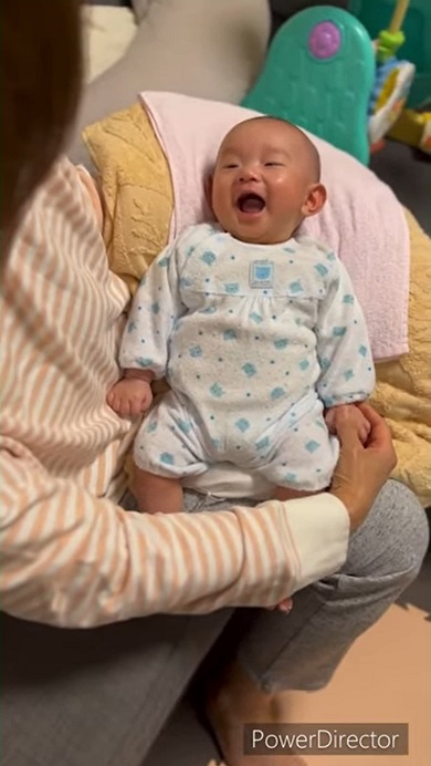 おばあちゃんに手をさすってもらいうれしくなった赤ちゃん