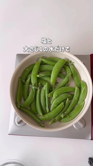 フライパンに塩と水、ヘタと筋が付いたスナップエンドウを入れて加熱