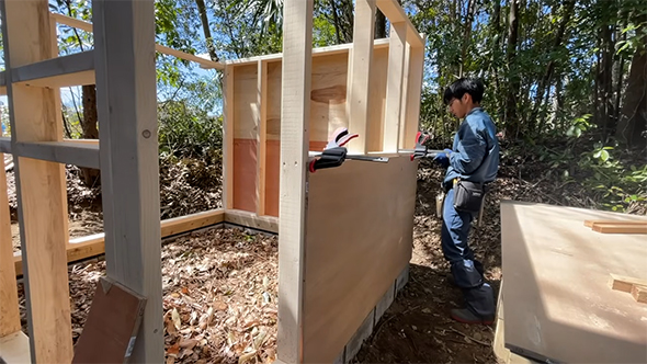 小屋に板をはる男性