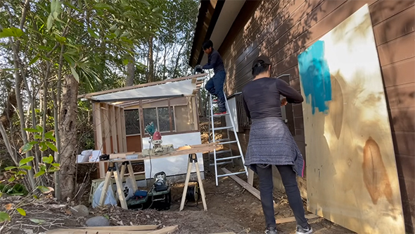 青い塗料を塗る女性