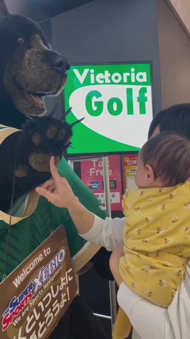 巨大な熊の置物に触れてびっくりする赤ちゃん