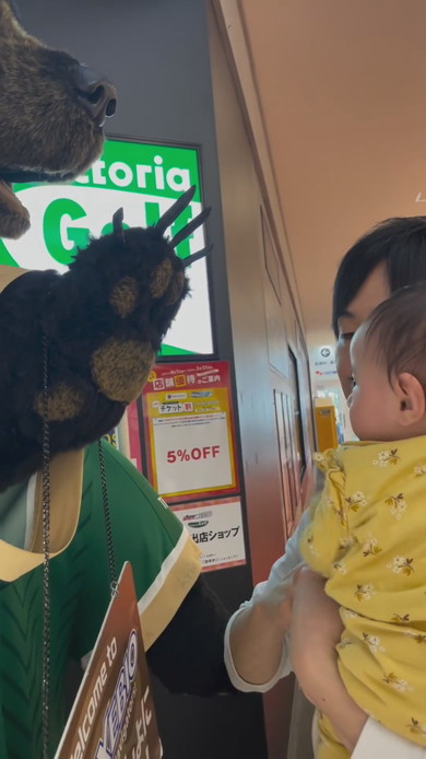 巨大な熊の置物に触れてびっくりする赤ちゃん