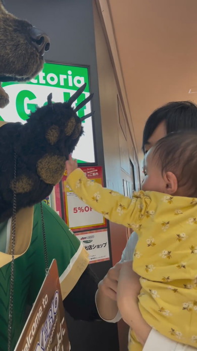 巨大な熊の置物に触れてびっくりする赤ちゃん