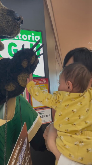 巨大な熊の置物に触れてびっくりする赤ちゃん