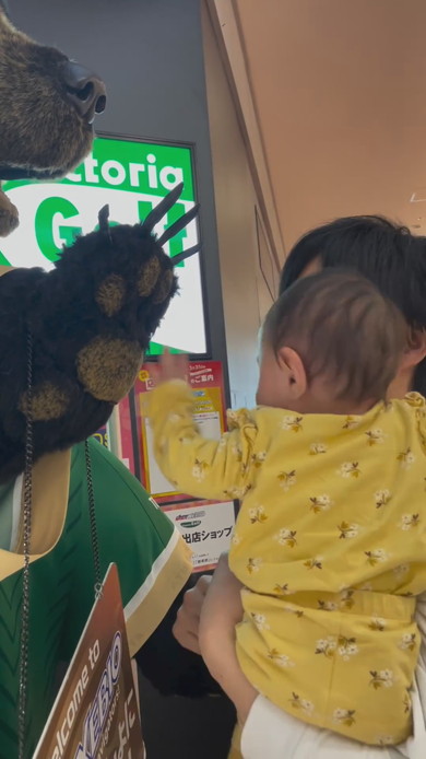巨大な熊の置物に触れてびっくりする赤ちゃん