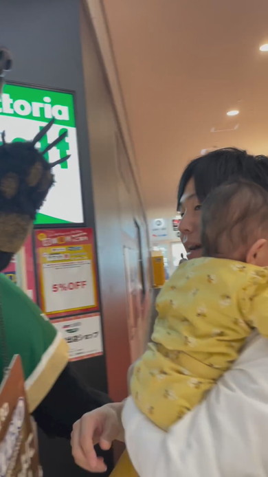 巨大な熊の置物に触れてびっくりする赤ちゃん