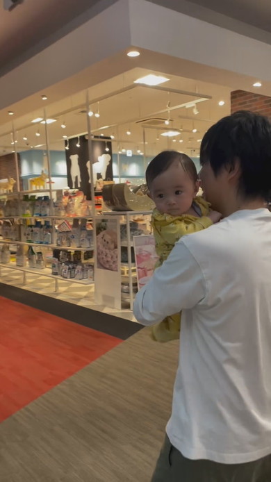 巨大な熊の置物に触れてびっくりする赤ちゃん