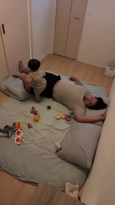 眠っているパパのそばで遊んでいる息子