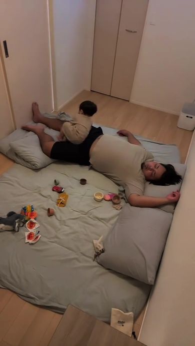 眠っているパパの足にすっぽり収まる息子
