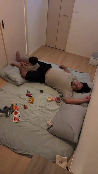 眠っているパパの足にすっぽり収まる息子
