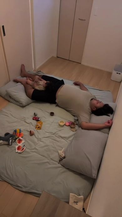 眠っているパパの足にすっぽり収まる息子
