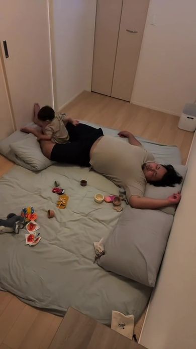 眠っているパパの足にすっぽり収まる息子