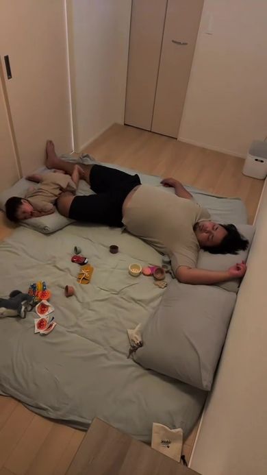 眠っているパパの足を枕にして寝る息子