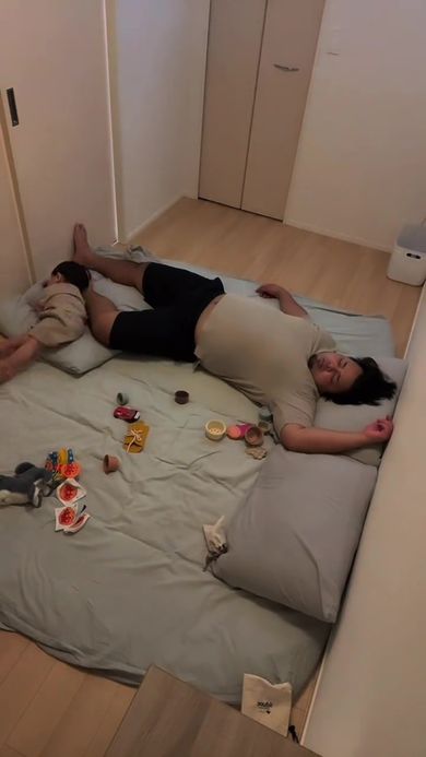 眠っているパパの足を枕にして寝る息子