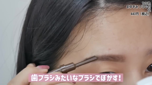 眉をブラシでぼかす女性