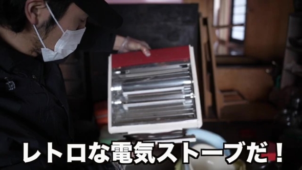 電気ストーブを持つ男性