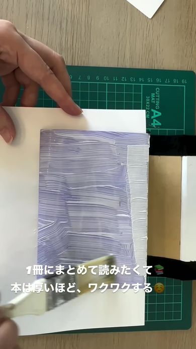 1冊のハードカバーの本にまとめるため見返しに接着剤を塗る