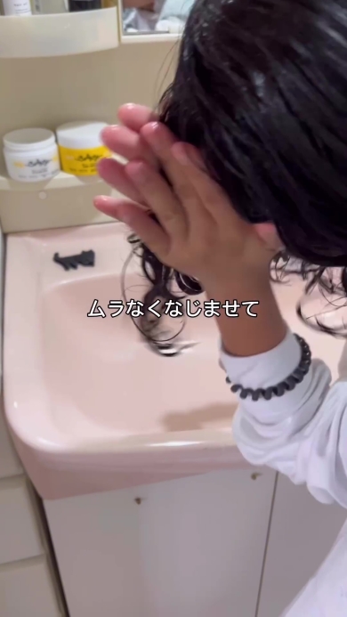 手で髪になじませる女の子