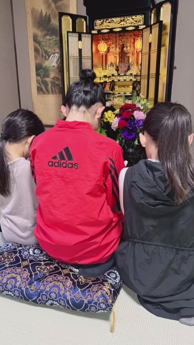 仏壇に手を合わせる三姉妹