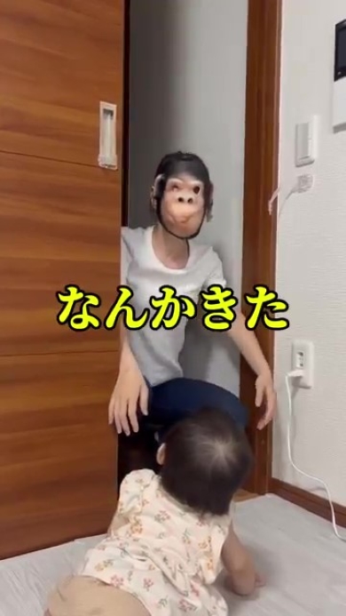 お面をかぶった女性を見つめる赤ちゃん