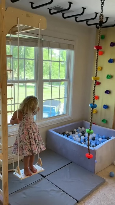 パパが作ったはしごやカラーボールのプール、ボルダリング設備などの前でブランコを楽しむ娘