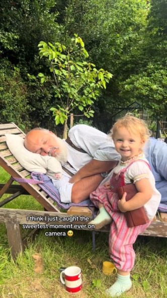 寝転がるおじいちゃんのそばに寄る女の子