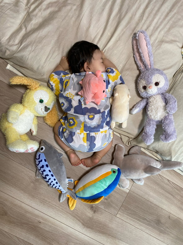 ぬいぐるみに囲まれて寝る赤ちゃん