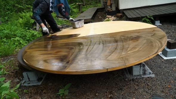 デッキの丸い床材に防腐塗料を塗っていく