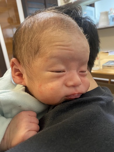 げっぷによりおじいちゃんのような顔になった赤ちゃん